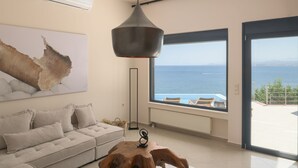 Een moderne woonkamer met een groot raam, een bank, een houten salontafel en een hanglamp.