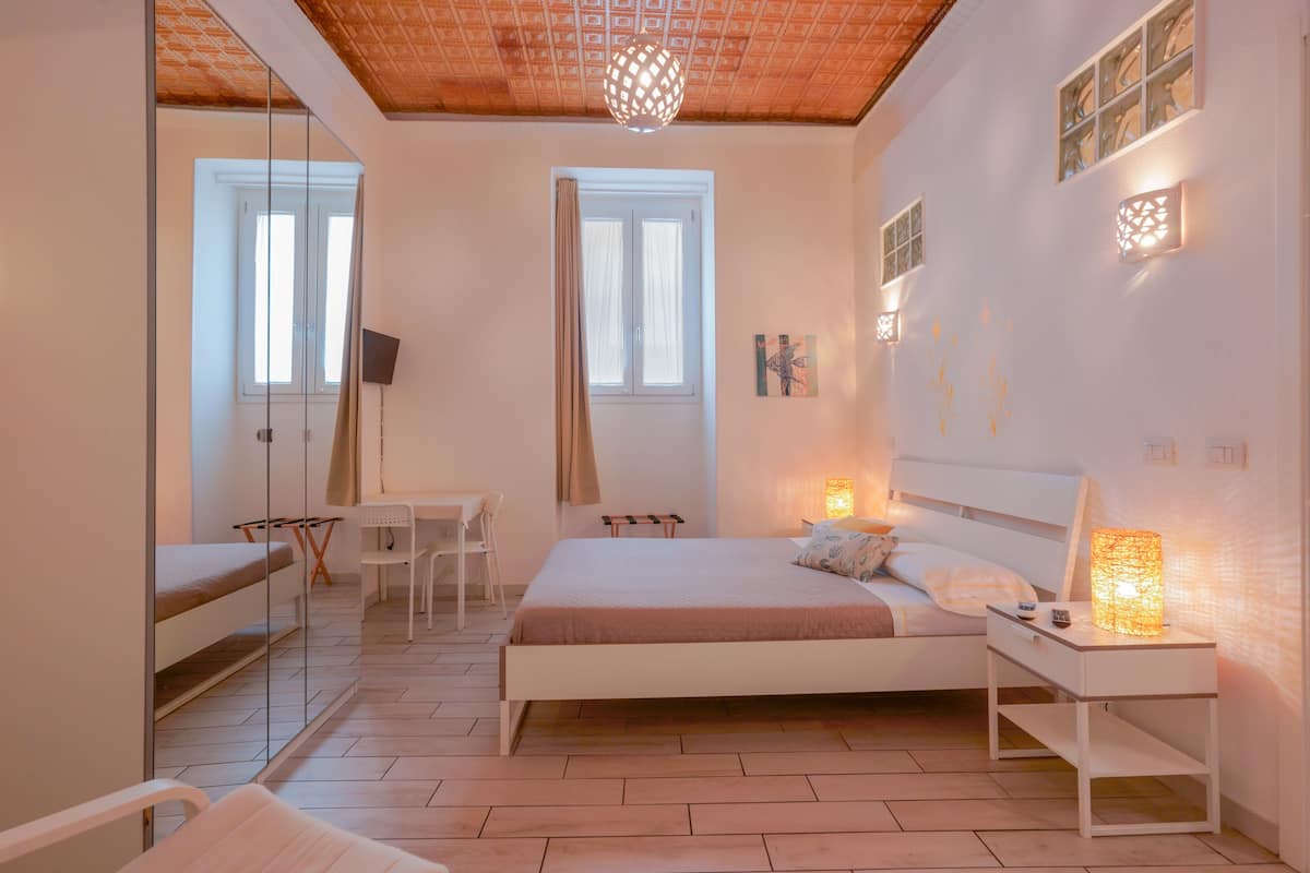 Ein Schlafzimmer mit einem Bett, einem Nachttisch, einer Lampe und einem Schreibtisch mit Stuhl.