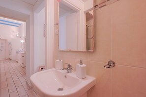 Un baño con lavamanos blanco, espejo y retrete.