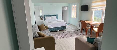 A hotel room with a bed, a desk, a chair, a sofa, and a television.