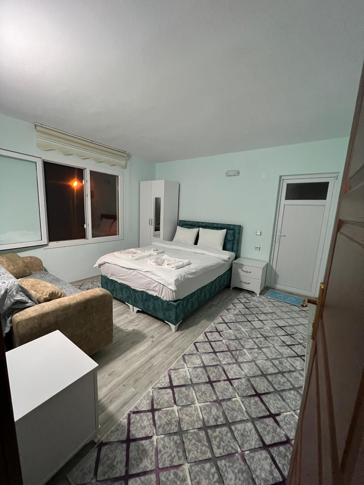 A bedroom with a bed, a wardrobe, a desk, and a chair.