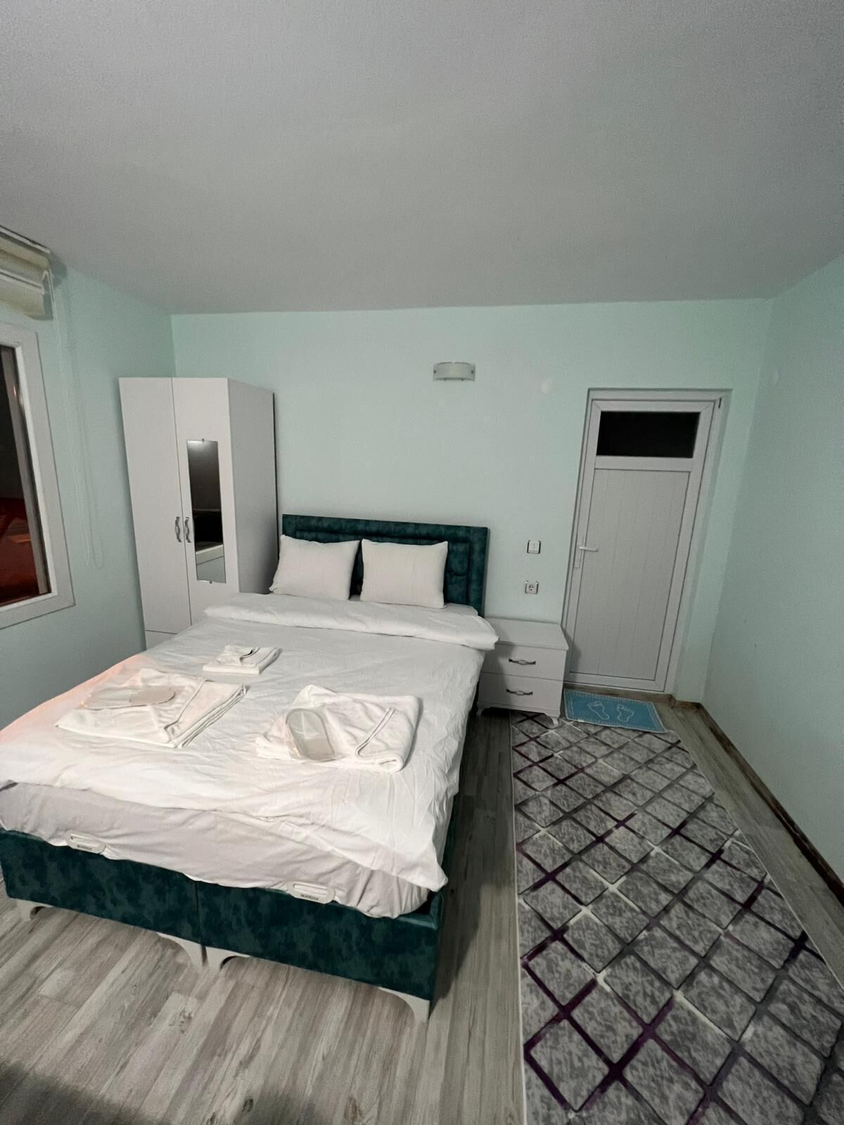 Een slaapkamer met een bed, een kledingkast, een nachtkastje en een deur.