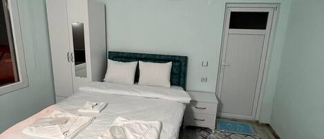 A bedroom with a bed, a wardrobe, a nightstand, and a door.