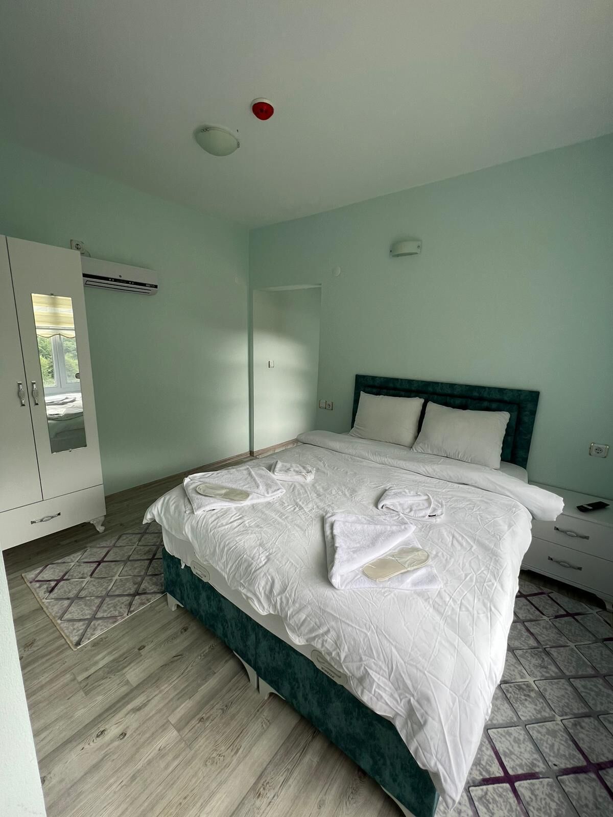 A bedroom with a bed, a wardrobe, an air conditioning unit, and a ceiling light.