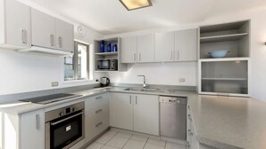 A modern kitchen with white cabinets, a stainless steel sink, and a built-in oven. - Welcome to Ballarat Bungalow. A Chic Central Stay with Easy Access to Queenstown’s Best! (Queenstown)