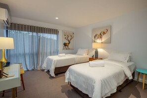 Two single beds with white linens and a desk area.