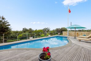 Relax by the serene pool surrounded by lush greenery and comfortable lounge chairs.