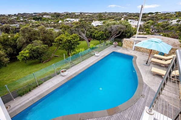 Relax by the pool surrounded by lush greenery and a residential view.
