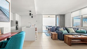 A modern living room with a sofa, coffee table, and a dining area with chairs and a table. - Aquaview Unit 304, 29 Canberra Tce, Kings Beach (Kings Beach)