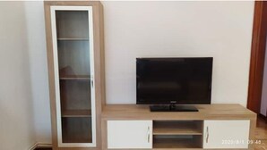 A TV stand with a flat-screen TV, a tall cabinet with multiple shelves, and a small white drawer unit. - Calle Lardero apartment (Logroño)