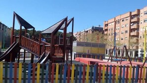 A playground with a wooden climbing structure and slides, surrounded by a colorful fence. - Calle Lardero apartment (Logroño)