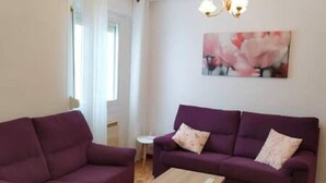 A living room with two purple sofas, a small round table, and a wooden coffee table. - Calle Lardero apartment (Logroño)