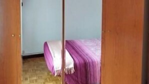 A room with a wooden wardrobe, a bed with a purple bedspread, and a wooden parquet floor. - Calle Lardero apartment (Logroño)
