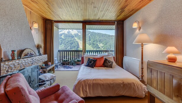 A bedroom with a bed, a desk, a chair, and a view of the mountains. - Les Marmottes du Morzena (Morzine)
