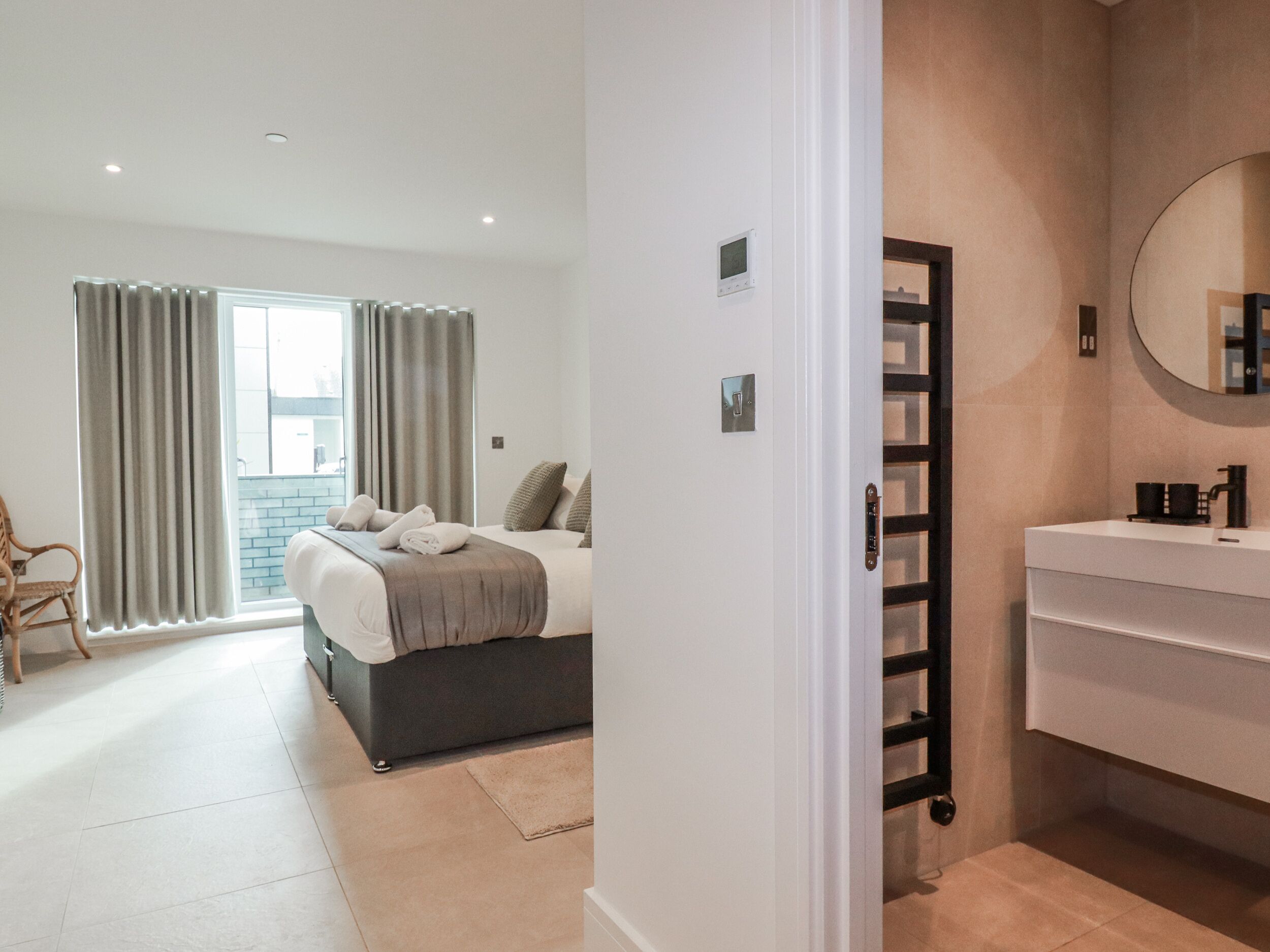 Habitación de hotel con cama, baño con espejo y vistas al exterior.