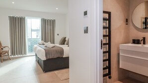 A hotel room with a bed, a bathroom with a mirror, and a view of the outside. - 13 Cliff Edge (Newquay)