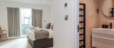 A hotel room with a bed, a bathroom with a mirror, and a view of the outside.