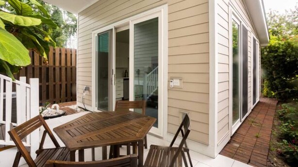 A patio with a wooden table and chairs, a white fence, and a wooden deck. - Lovely near Forsyth Park (Savannah)