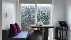 A modern living room with a black sofa, a round exercise ball, a small table with a teapot, and a music stand. - Lovely near Forsyth Park (Savannah)