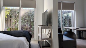 A bedroom with a bed, a TV on a stand, a desk, and a chair. - Lovely near Forsyth Park (Savannah)