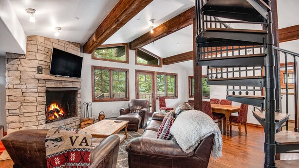 A cozy living room with a stone fireplace, leather furniture, and a spiral staircase. - Luxurious condominium in Perfect Location on Bridge Street, Near Gondolda 1!! (Vail)