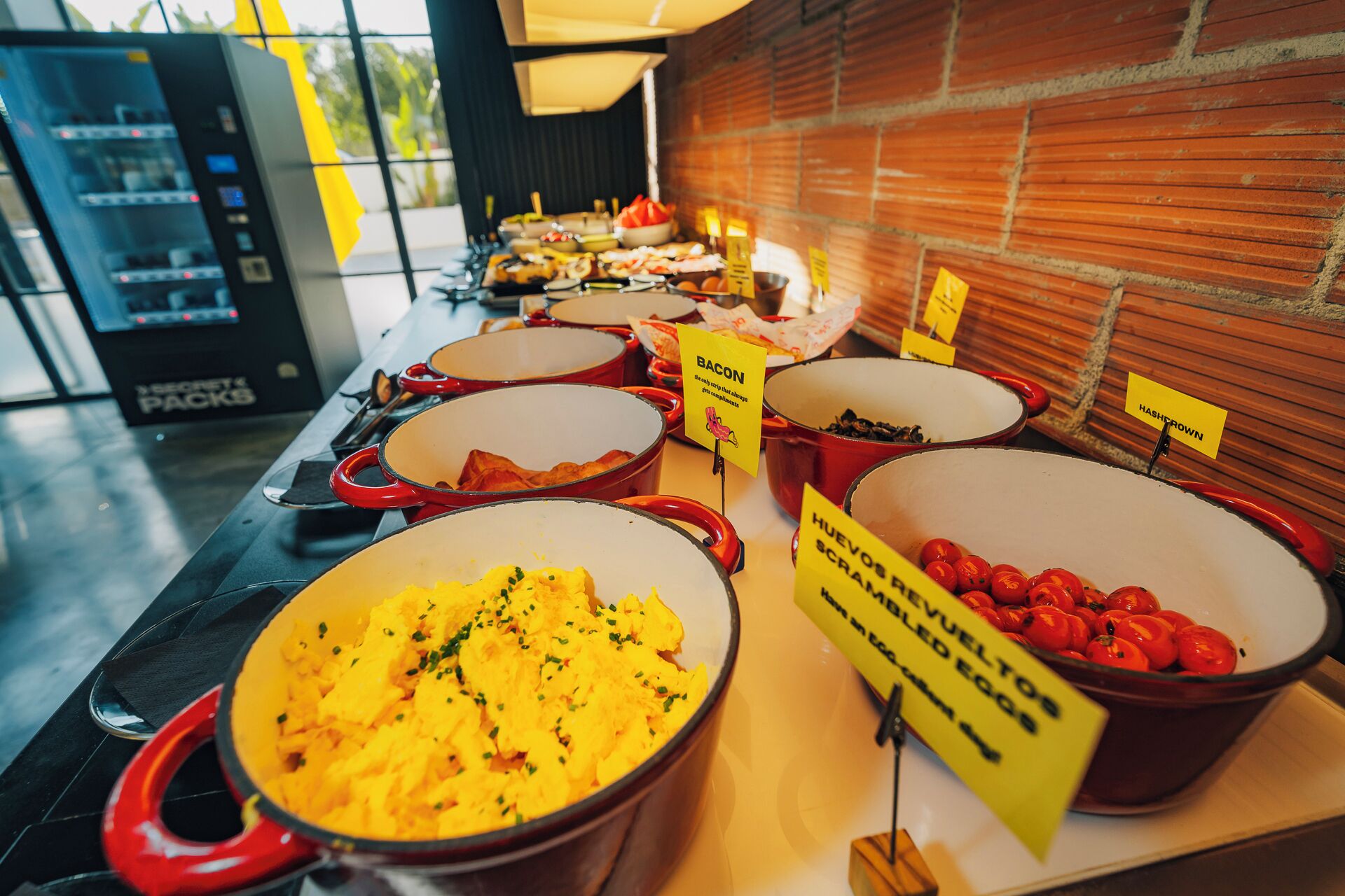 Un buffet proposant divers plats, notamment des œufs brouillés, du bacon et des tomates.