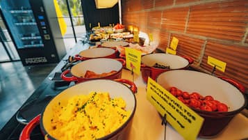 Un buffet proposant divers plats, notamment des œufs brouillés, du bacon et des tomates.