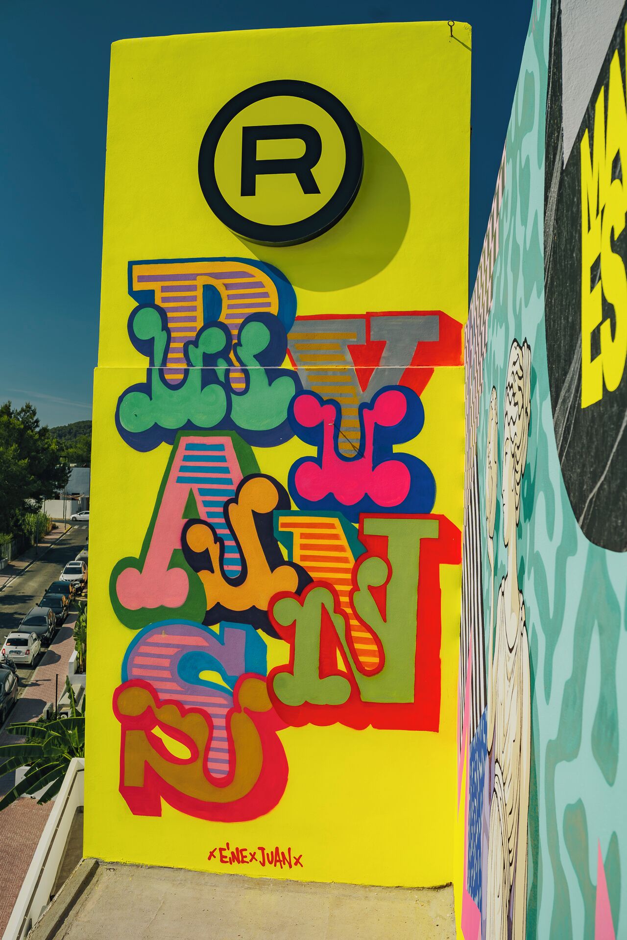 Un letrero colorido con estilo graffiti y un gran símbolo 'R' en la parte superior.