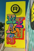 Un letrero colorido con estilo graffiti y un gran símbolo 'R' en la parte superior.