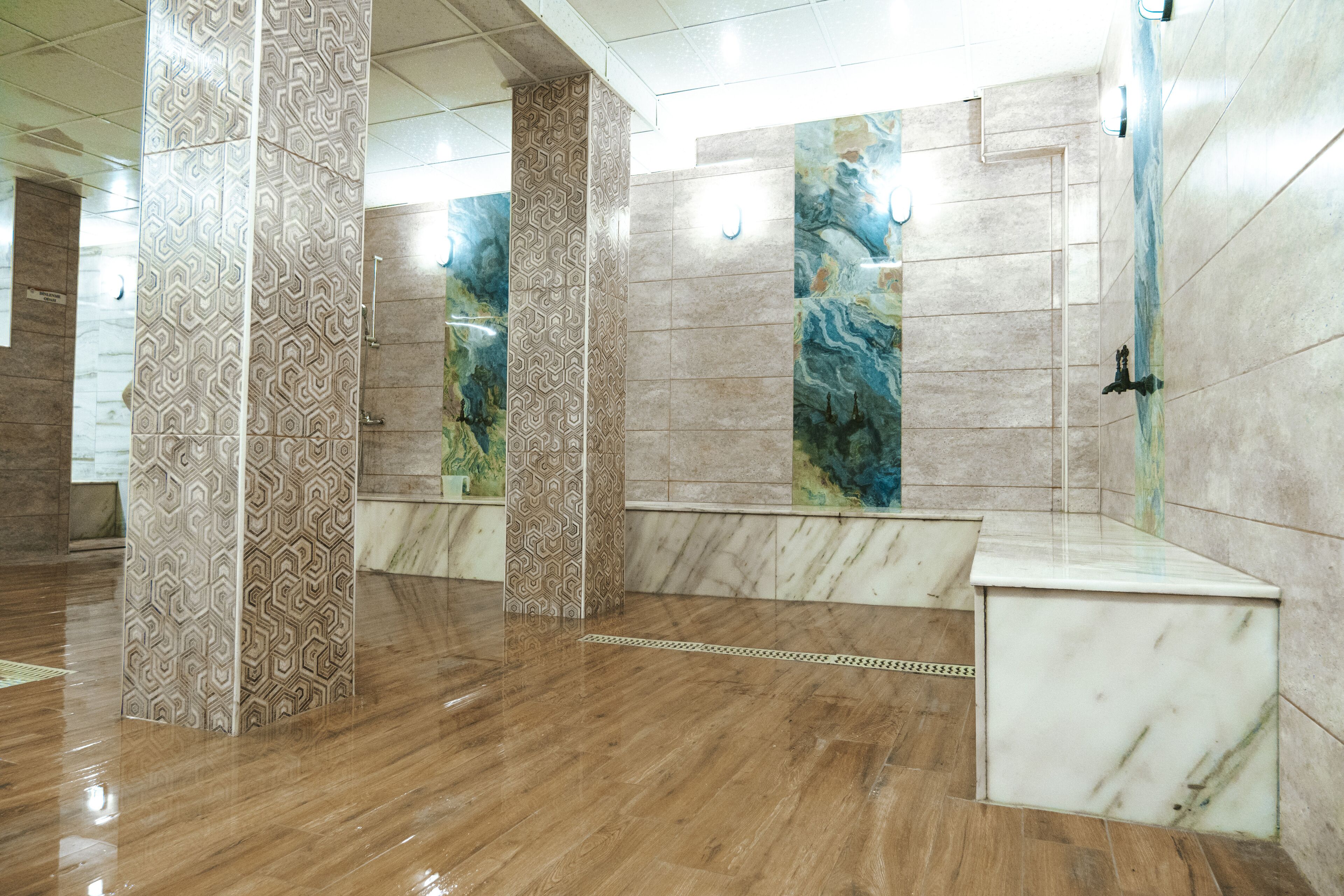 Un bagno moderno con pareti in marmo, pavimento in legno e lavandino bianco.
