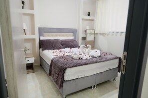 A neatly arranged bedroom with a bed, bedside tables, a mirror, and a wardrobe. - Merkür Hotel (Ihsaniye)