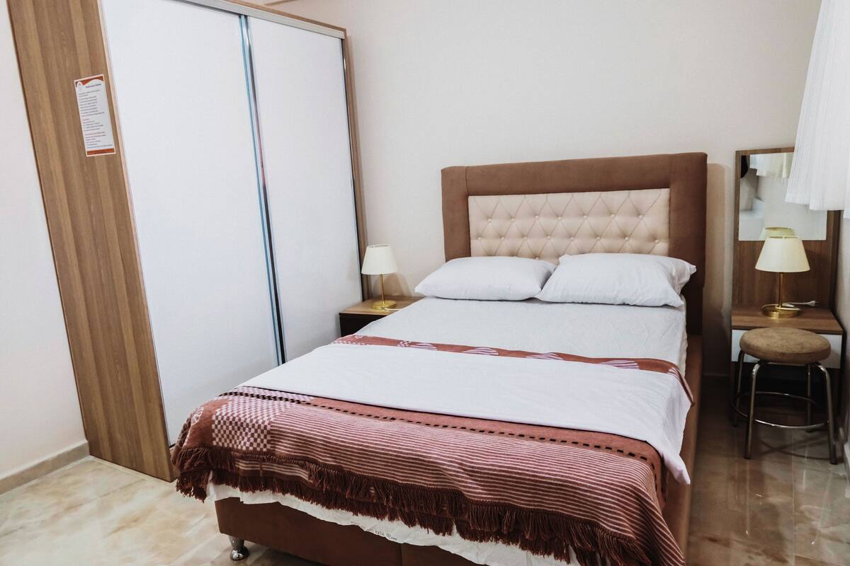 A bedroom with a bed, nightstands, a chair, and a wardrobe.