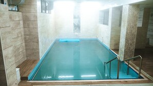 A swimming pool with a tiled interior, a wooden floor, and a metal railing. - Merkür Hotel (Ihsaniye)