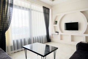 A modern living room with a black table, a sofa, and a TV mounted on a white wall.