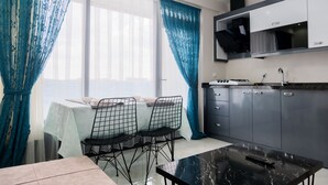 A modern kitchen with grey cabinets, a black countertop, and a dining area with a table and chairs. - Merkür Hotel (Ihsaniye)