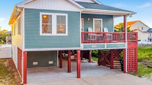 Una casa de dos pisos con un porche cubierto y una pequeña terraza.