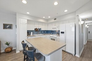 Une cuisine moderne avec des meubles blancs, un îlot central et un coin repas avec des chaises.
