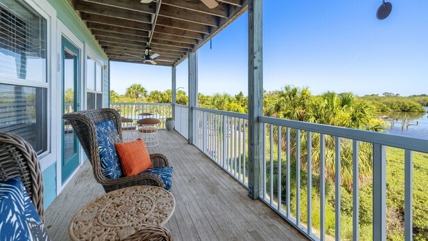 A covered porch with wicker furniture, a ceiling fan, and a view of a water body. - The Skimmer Condo: Downtown on the Bay - Nature Views - Bird watching (Cedar Key)