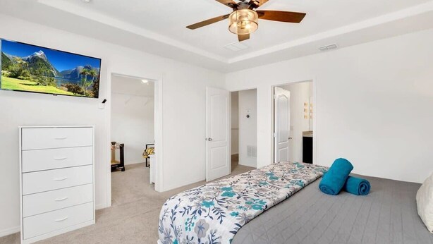 A bedroom with a bed, a ceiling fan, a wardrobe, and a painting on the wall. - Private Views & Theme Rooms, Perfect for Families! (Davenport)