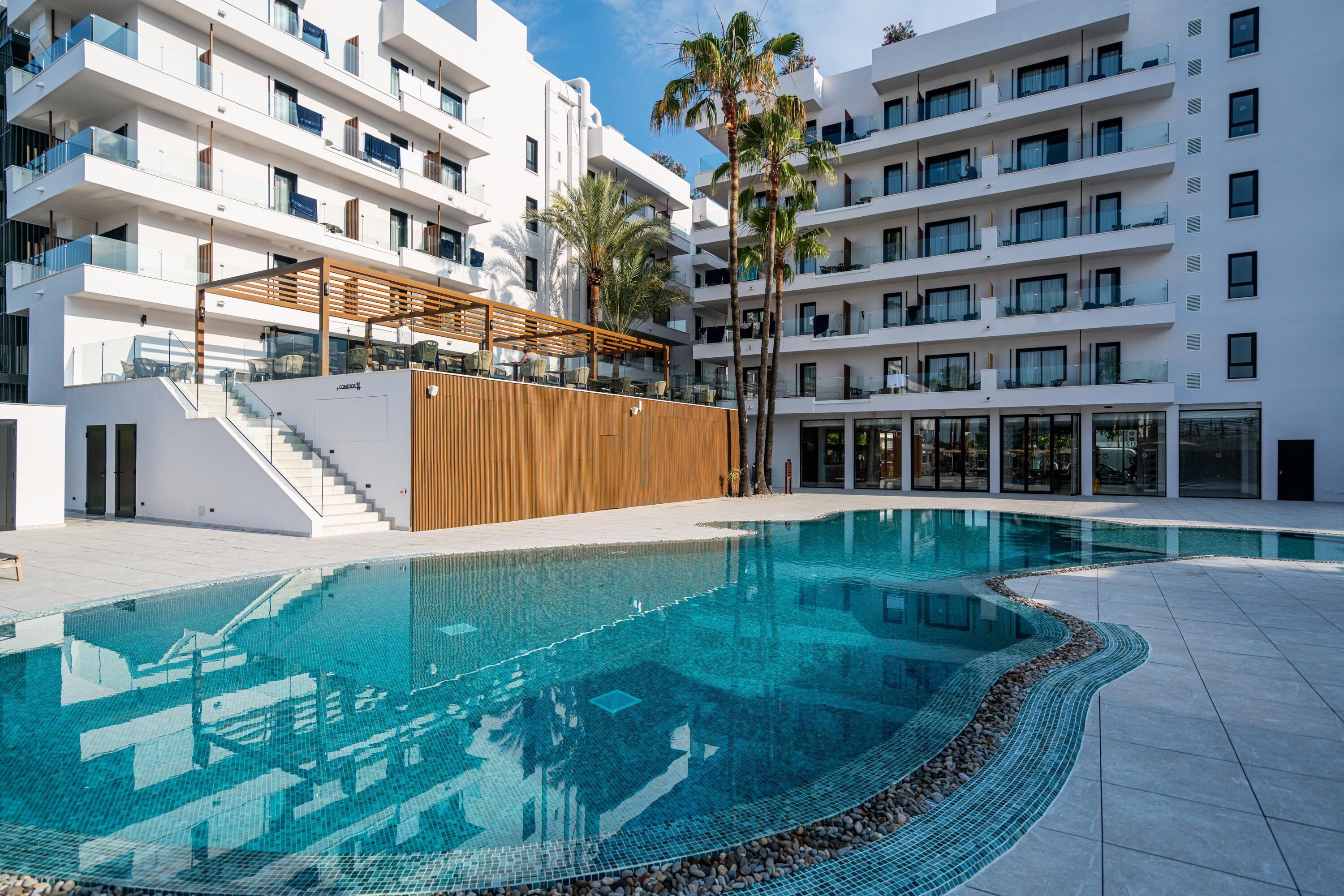 Ein modernes Hotel mit Schwimmbad, mehreren Balkonen und einer Holzterrasse.
