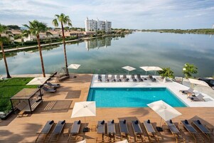 Una piscina al aire libre, sombrillas, sillones reclinables de piscina