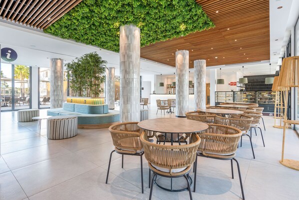 A modern indoor space with round tables and wicker chairs, a green wall, and a wooden ceiling. - THB Bamboo Alcudia Hotel - Adults Only (Alcúdia)