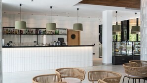 A modern bar area with wicker chairs, a counter with bottles, and a glass display case. - THB Bamboo Alcudia Hotel - Adults Only (Alcúdia)