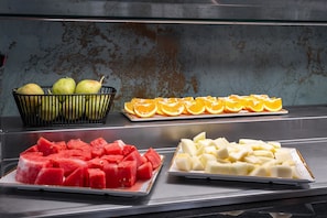 Buffet com diversas frutas, incluindo melancia, laranjas e peras.