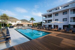 Una piscina al aire libre, sombrillas, sillones reclinables de piscina