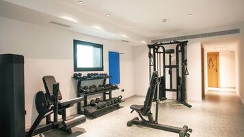 Un gimnasio con máquinas de pesas, mancuernas y barra para dominadas.