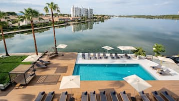 Una piscina al aire libre, sombrillas, sillones reclinables de piscina