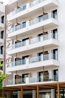 Un edificio de varios pisos con balcones, ventanas amplias y un diseño arquitectónico moderno.