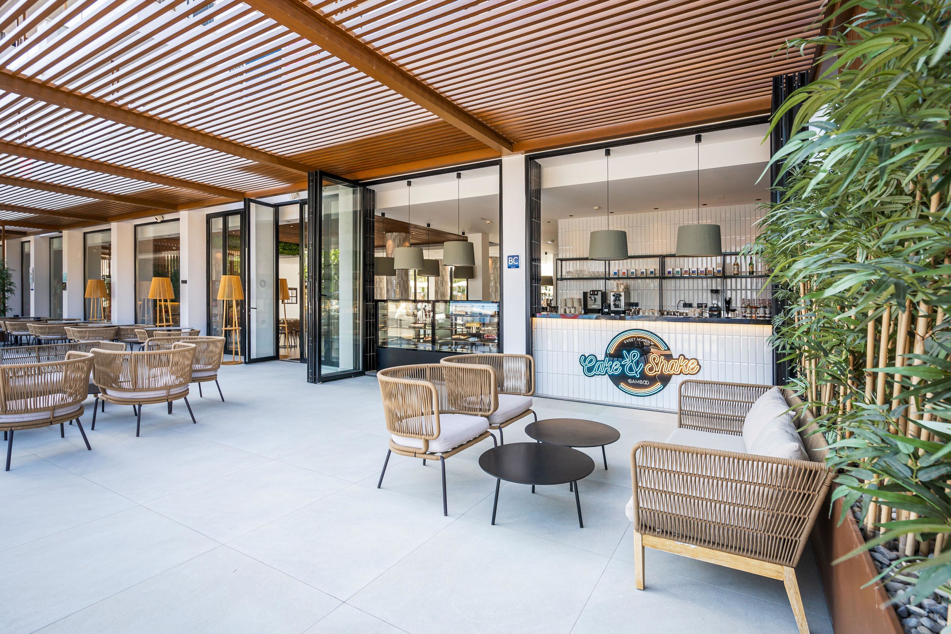 Un grand espace extérieur aménagé avec des meubles en osier et un comptoir de bar.
