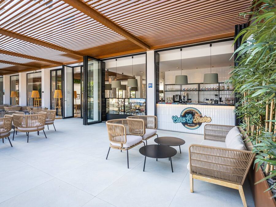 Un grand espace extérieur aménagé avec des meubles en osier et un comptoir de bar.